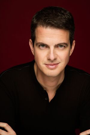 Philippe Jaroussky looking confident in front of a red background
